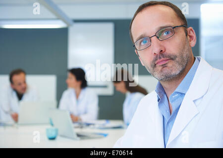 Portrait of male doctor, colleagues having discussion behind Stock Photo