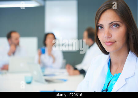 Portrait of female doctor, colleagues having discussion behind Stock Photo