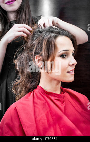 Female hairdresser pinning back young woman's hair in hair salon Stock Photo