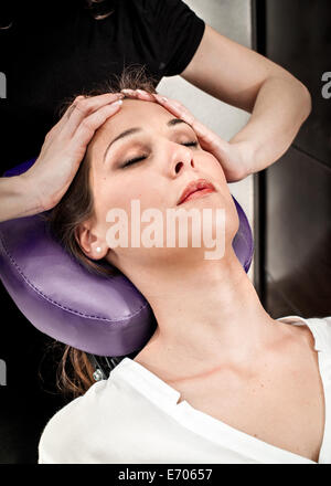 Female masseur massaging young woman's forehead in beauty salon Stock Photo