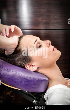 Female masseur massaging young woman's head in beauty salon Stock Photo