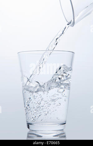 Clear water pouring from jug into drinking glass Stock Photo