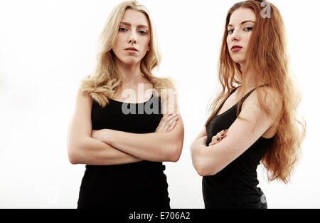 Studio portrait of two young woman with arms folded Stock Photo