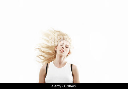 Studio portrait of young woman shaking long blond hair