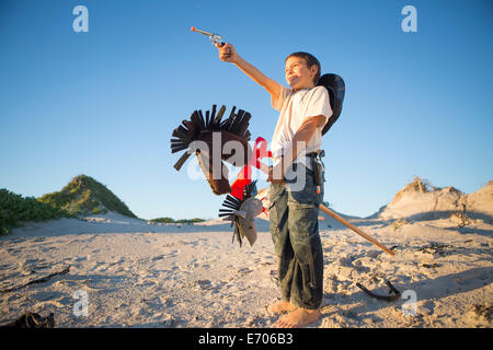 Boy dressed as cowboy with hobby horse in sand dunes Stock Photo