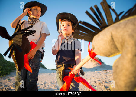 Two brothers dressed as cowboys with toy gun and hobby horse's Stock Photo