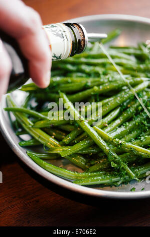 Person pouring sauce on green beans Stock Photo