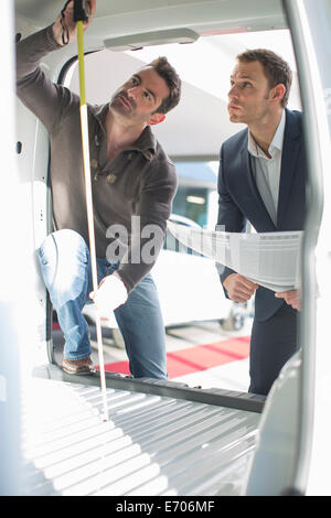 Customer and salesman checking vehicle interior height in car dealership Stock Photo