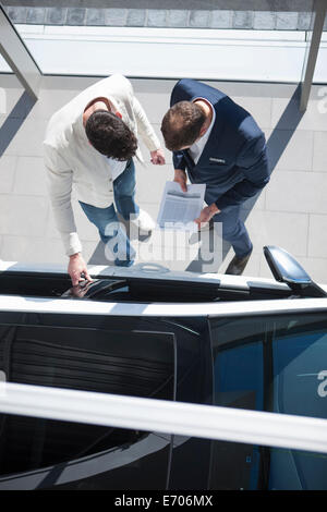 Overhead view of salesman and customer looking at new car in car dealership Stock Photo