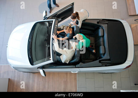 Overhead view of family trying out convertible car in car dealership Stock Photo