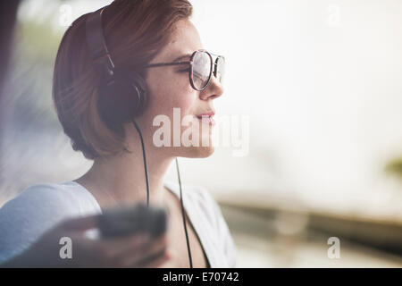 Mid adult woman listening to music on headphones