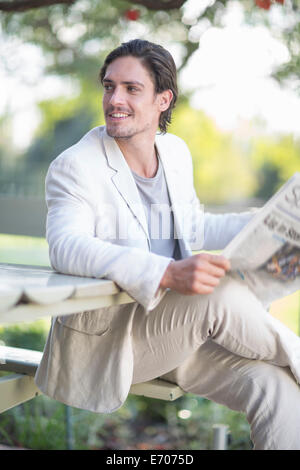 Businessman reading newspaper in park Stock Photo