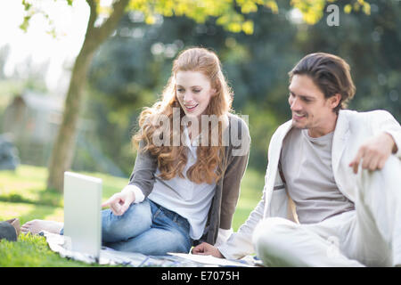 Businessman and female colleague using laptop in park Stock Photo