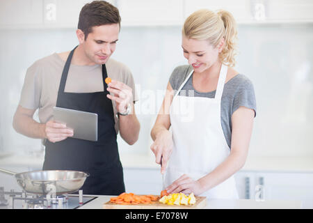 Couple chopping and tasting sliced vegetables in kitchen Stock Photo