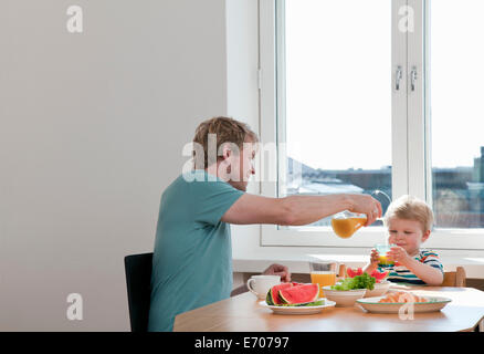 Father and toddler son having breakfast at kitchen table Stock Photo