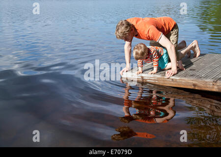 Father and son looking down into lake from pier, Somerniemi, Finland Stock Photo