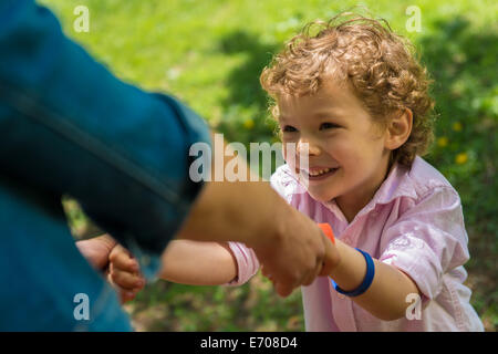 Young mother holding son's hands in park Stock Photo