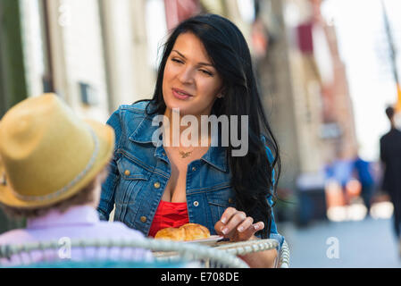 Young mother and son having cake at sidewalk cafe Stock Photo