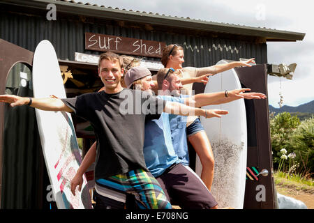 Group portrait of five young adult surfer friends posing with arms outstretched Stock Photo