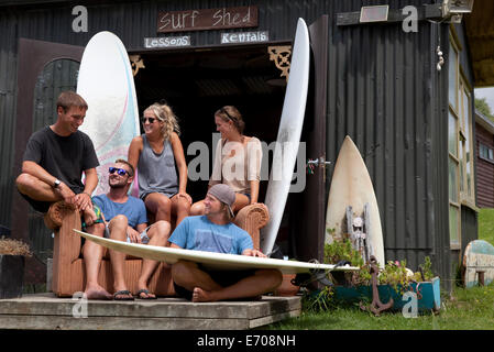 Five young adult surfer friends chatting outside shed Stock Photo