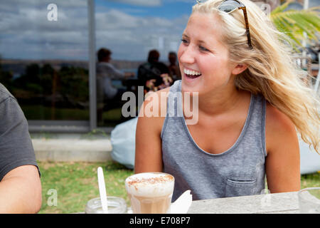 Young woman sitting at picnic bench drinking glass of latte Stock Photo