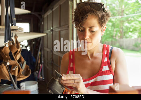 Mid adult woman preparing sander to restore furniture in garage Stock Photo