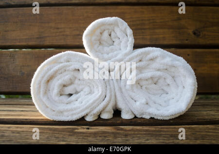 https://l450v.alamy.com/450v/e70gpk/crisp-white-towels-are-rolled-and-placed-on-the-wooden-bench-of-an-e70gpk.jpg