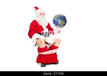 Santa holding the planet in hand seated on toilet isolated on white background Stock Photo