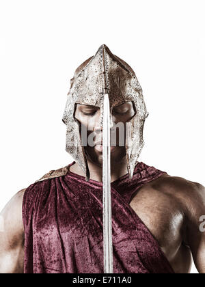 Studio portrait of poised young man dressed as gladiator with helmet and sword Stock Photo