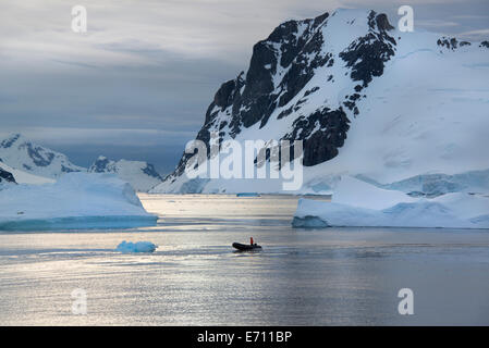People in small inflatible zodiac rib boats passing icebergs and ice floes islands of the Antarctic Peninsula. Stock Photo