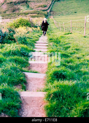 Two women walking along a cliff path, walking down a set of steep steps. Stock Photo
