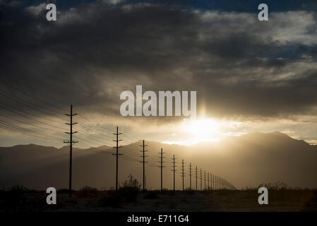 Power lines in rows across the landscape, against a darkening sky. Stock Photo