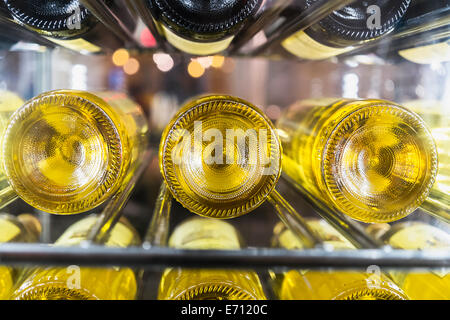 View of bottles of white wine laid down on a rack in a cellar. Stock Photo