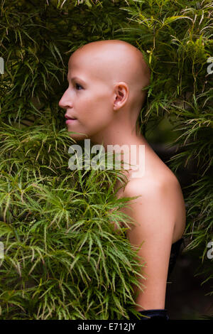 Side view portrait of young woman with cancer in foliage Stock Photo