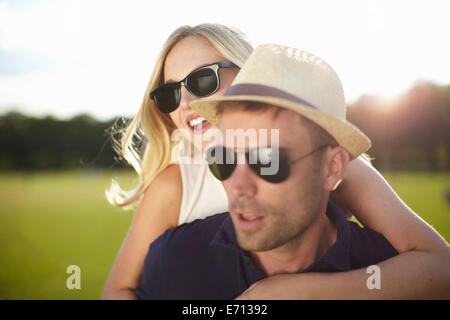 Young woman with arms around boyfriend in park Stock Photo