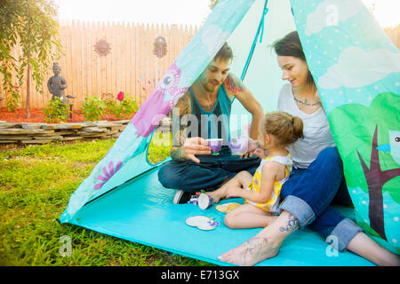 Young couple and toddler daughter playing teatime in tent Stock Photo