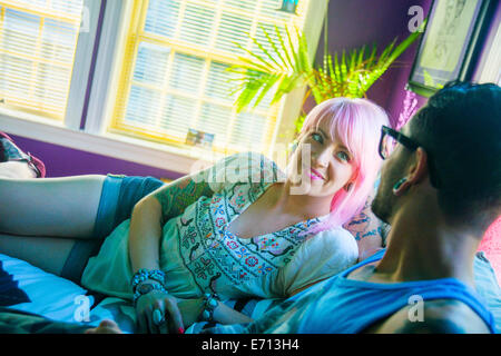 Funky couple reclining on bed Stock Photo