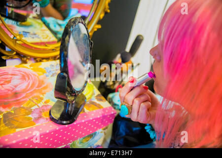 Young woman with pink hair putting on pink lipstick Stock Photo