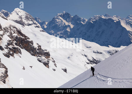 Snowy highlands with a lone touring skier skiing on fresh snow Stock Photo