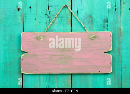Distressed pink blank sign hanging on antique green old wooden door Stock Photo