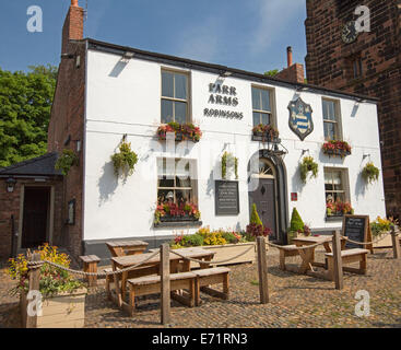 Old English pub with white painted facade, colourful flowers in window boxes, and outdoor dining area at village of Grappenhall Stock Photo