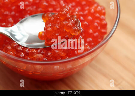 Red caviar on a spoon in a glass bowl. Closeup. Stock Photo