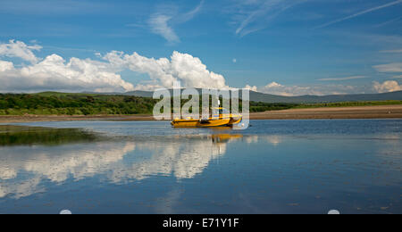 Yellow boat, blue sky and white clouds reflected in calm blue water of ocean at Ravenglass, coastal village in Cumbria England Stock Photo