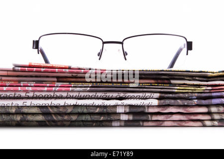 Stack of newspapers and eye glasses, isolated on white background. Stock Photo