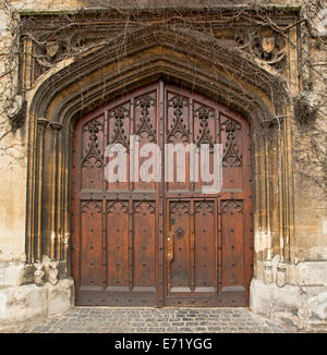 Spectacular rich brown double wooden doors with intricate carving and decorative arched stone surrounds of historic building in Oxford, England Stock Photo