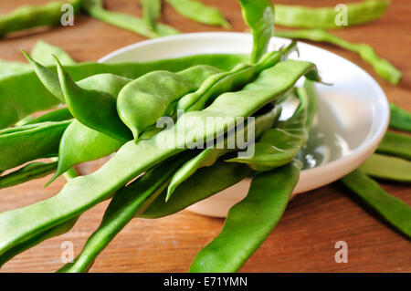 a bowl with green bean pods on a rustic wooden table Stock Photo