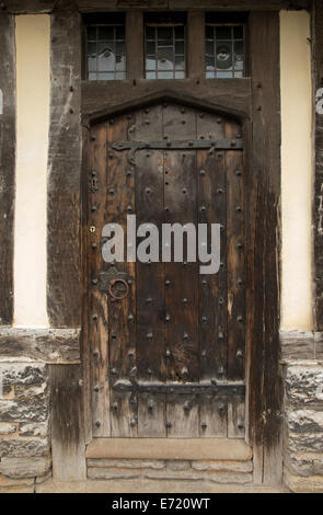 Old brown weathered wooden door with metal studs and ornate hinges - on historic building  in Stratford-upon-Avon, England Stock Photo