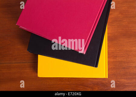 Top view of stacked colorful books on wooden table. Stock Photo