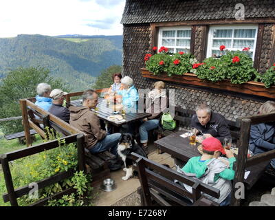 Guests of a hiker inn are sitting on a terrace in front of the guesthouse 'Hintereck' near Gütenbach in the southern part of Black Forest (Germany), on August, 24, 2014. Stock Photo