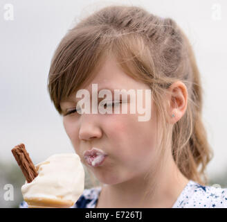 Pretty young girl eating ice cream in the summer sun by the seaside Stock Photo